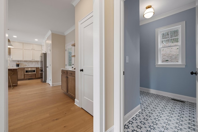 hallway featuring ornamental molding and light hardwood / wood-style flooring