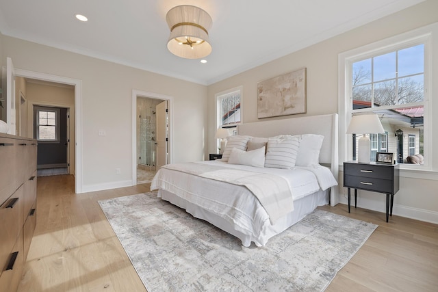 bedroom featuring crown molding, connected bathroom, light hardwood / wood-style floors, and multiple windows