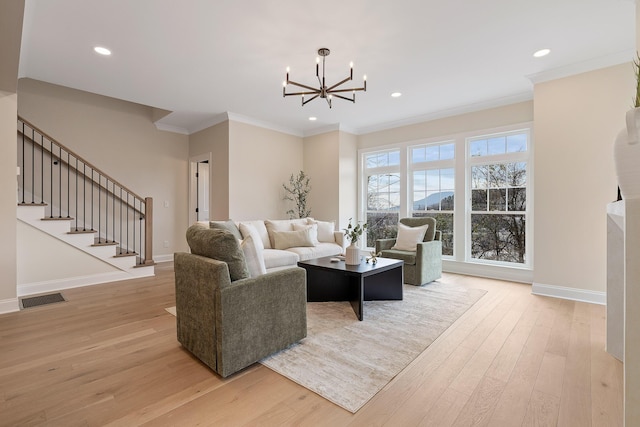 living room with crown molding, a chandelier, and light hardwood / wood-style floors