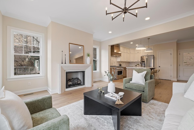 living room featuring ornamental molding, an inviting chandelier, and light hardwood / wood-style floors