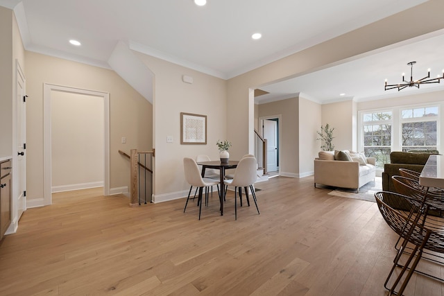 dining area featuring crown molding, a notable chandelier, and light hardwood / wood-style flooring