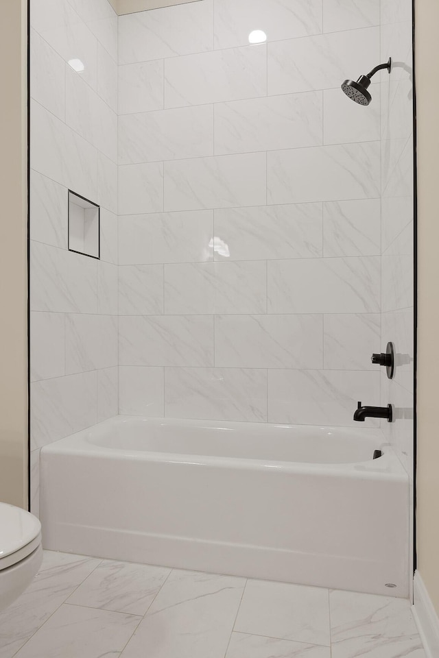 bathroom featuring tiled shower / bath combo and toilet