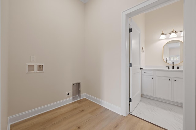 laundry area featuring electric dryer hookup, sink, and light hardwood / wood-style flooring