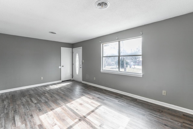 spare room featuring dark wood-type flooring and a textured ceiling