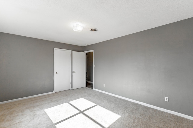 unfurnished bedroom featuring light colored carpet and a textured ceiling