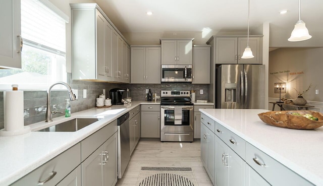 kitchen featuring pendant lighting, sink, gray cabinets, appliances with stainless steel finishes, and backsplash