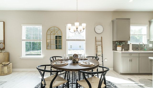 dining space featuring light hardwood / wood-style flooring, sink, a wealth of natural light, and a chandelier