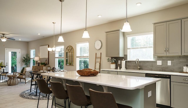 kitchen with sink, decorative light fixtures, gray cabinets, dishwasher, and a kitchen island