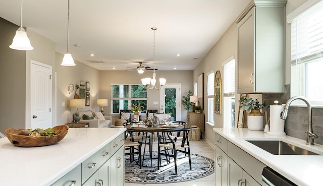 kitchen with pendant lighting, sink, dishwasher, backsplash, and a notable chandelier