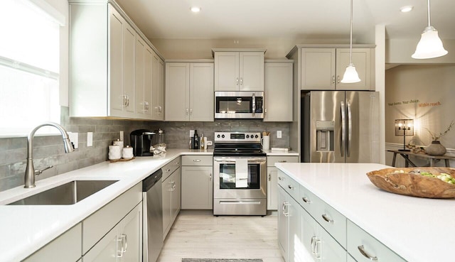 kitchen with sink, hanging light fixtures, light hardwood / wood-style flooring, stainless steel appliances, and decorative backsplash