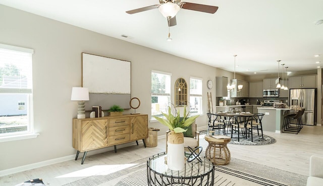 living area with ceiling fan with notable chandelier and light hardwood / wood-style flooring