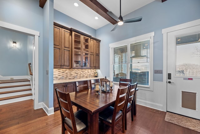 dining area featuring ceiling fan, dark hardwood / wood-style floors, and beamed ceiling