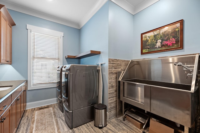 washroom with crown molding, cabinets, washing machine and clothes dryer, and light wood-type flooring