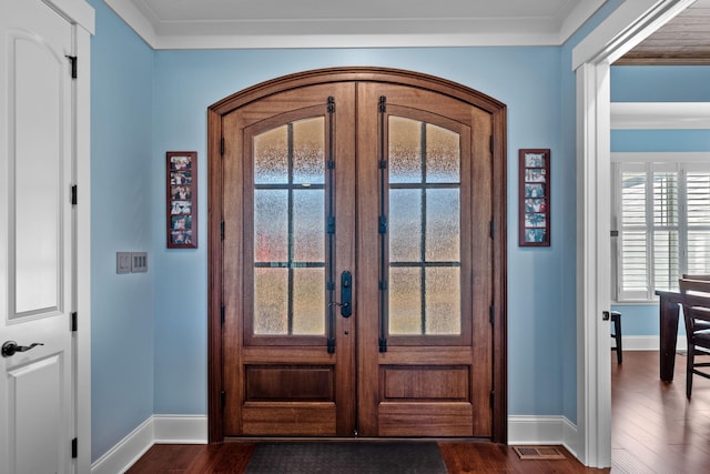 entrance foyer featuring dark wood-type flooring, ornamental molding, and french doors