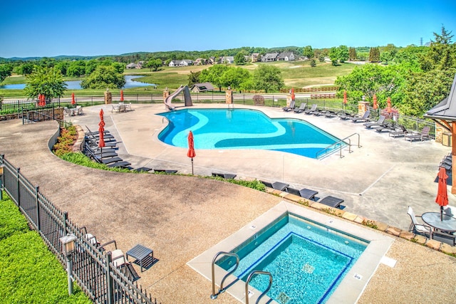 view of pool featuring a water view, a hot tub, and a patio