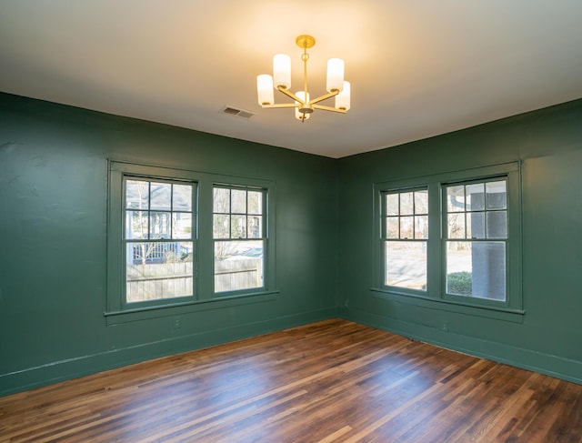 spare room with dark hardwood / wood-style floors and a chandelier