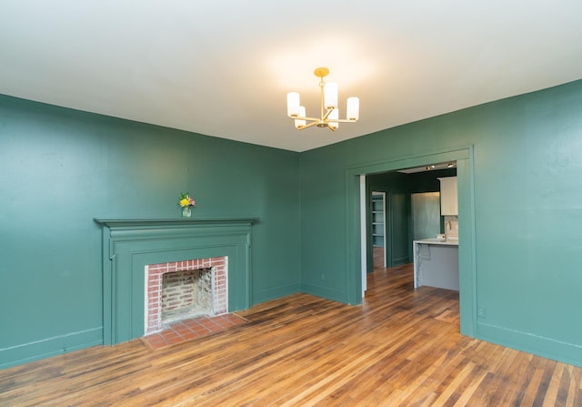 unfurnished living room featuring wood-type flooring, a fireplace, and a chandelier