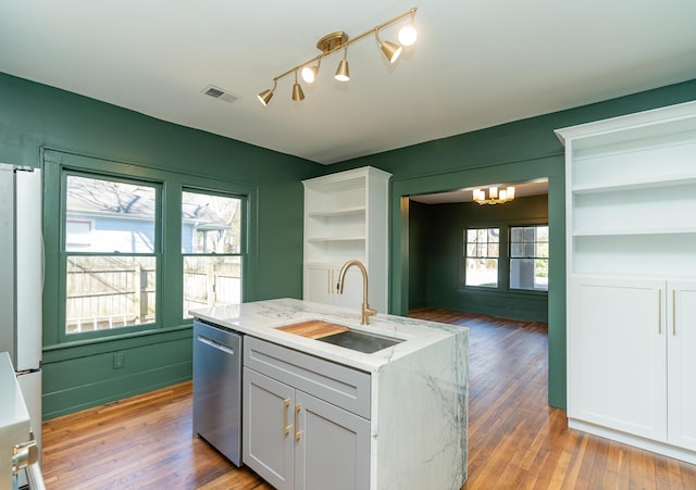 kitchen with sink, white cabinetry, light stone counters, stainless steel dishwasher, and light hardwood / wood-style floors