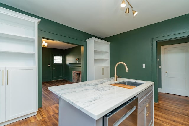 kitchen featuring dishwasher, an island with sink, sink, and dark hardwood / wood-style floors