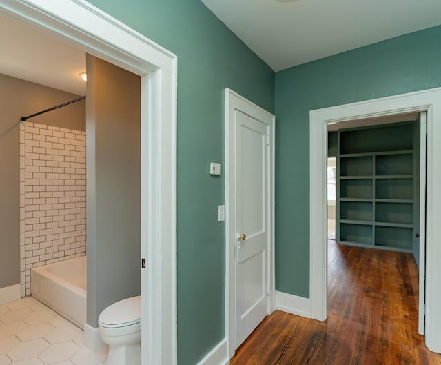 bathroom with tiled shower / bath combo, hardwood / wood-style floors, and toilet