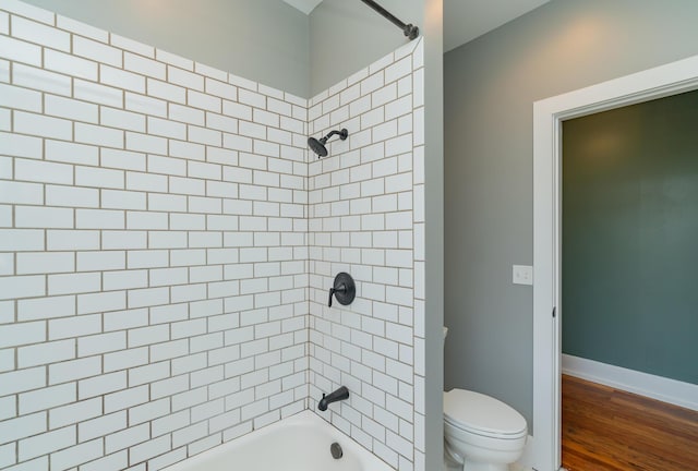 bathroom featuring tiled shower / bath, toilet, and hardwood / wood-style floors