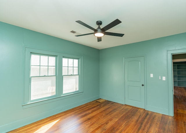 empty room with ceiling fan and dark hardwood / wood-style flooring