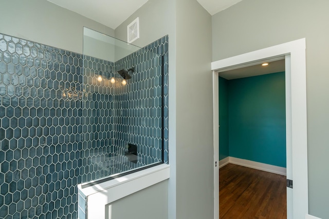 bathroom with wood-type flooring and a tile shower