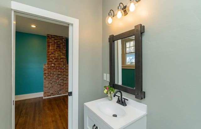 bathroom featuring brick wall, vanity, and hardwood / wood-style floors