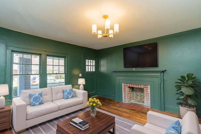 living room featuring a brick fireplace, hardwood / wood-style floors, and a notable chandelier