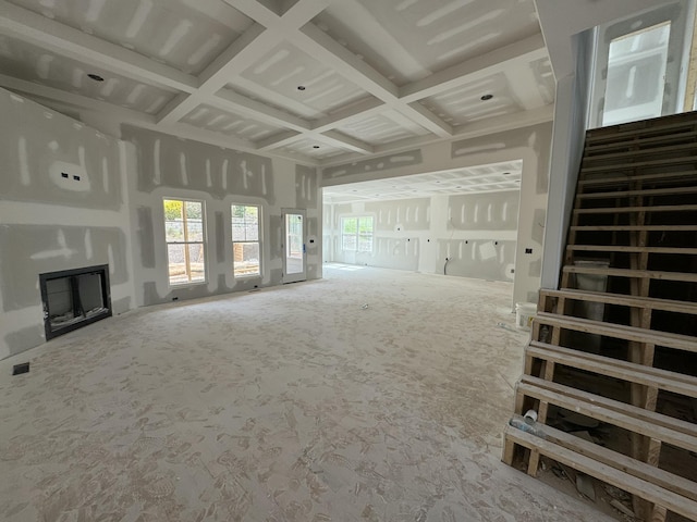 unfurnished living room featuring stairs, coffered ceiling, a fireplace, and visible vents