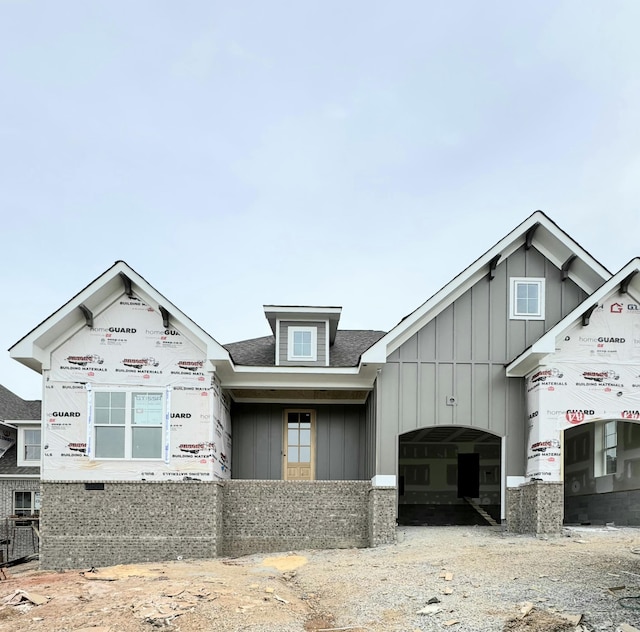 unfinished property featuring a garage, roof with shingles, and board and batten siding