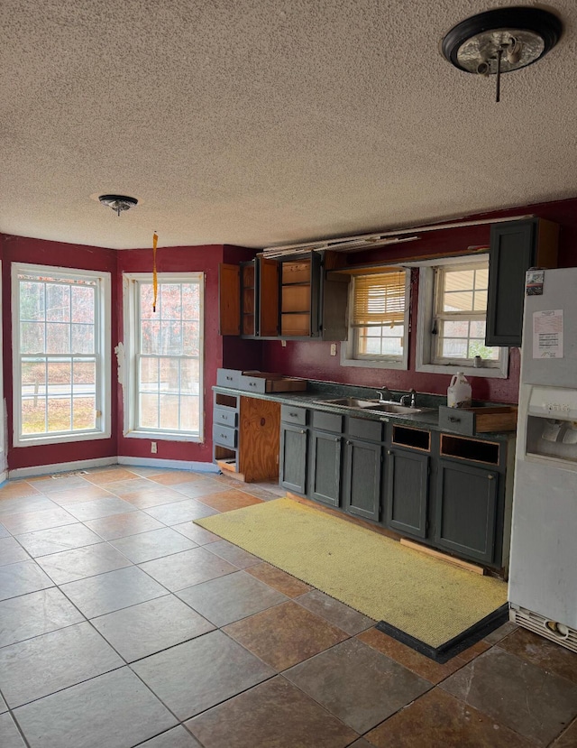 kitchen featuring pendant lighting, white refrigerator with ice dispenser, sink, and a wealth of natural light