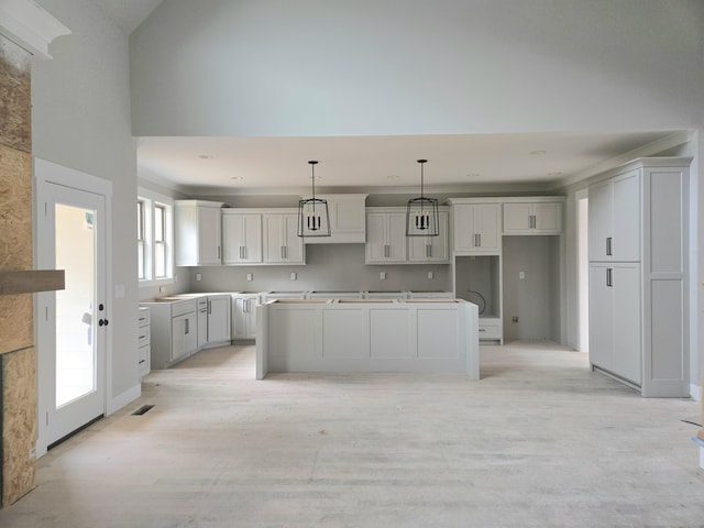 9892 Trestle Cir Unit 50, Ooltewah, TN 37363 - kitchen with light wood-style flooring, white cabinetry, a kitchen island, decorative light fixtures, and baseboards