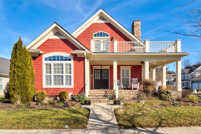 view of front of home featuring a front lawn, a balcony, and covered porch