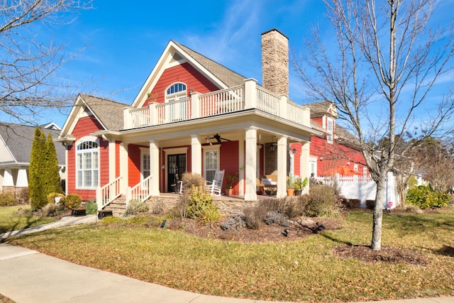 view of front of home featuring ceiling fan, a front yard, a balcony, and a porch