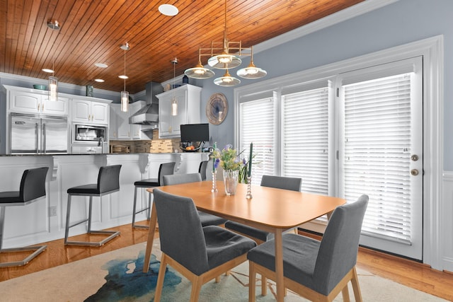 dining space featuring crown molding, light hardwood / wood-style flooring, and wooden ceiling