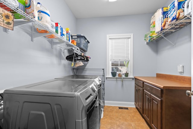 washroom with light tile patterned flooring, independent washer and dryer, and cabinets