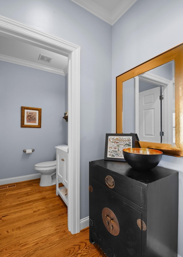 bathroom with crown molding, wood-type flooring, toilet, and vanity