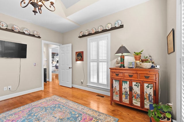 sitting room with hardwood / wood-style floors and a chandelier