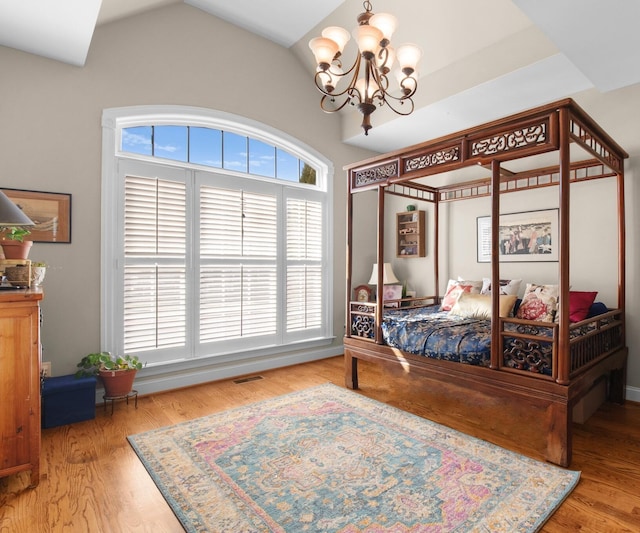 bedroom featuring wood-type flooring, a chandelier, and vaulted ceiling