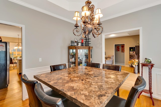 dining room with crown molding, a chandelier, and light wood-type flooring