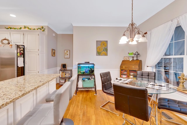 dining space with an inviting chandelier, crown molding, and light hardwood / wood-style flooring