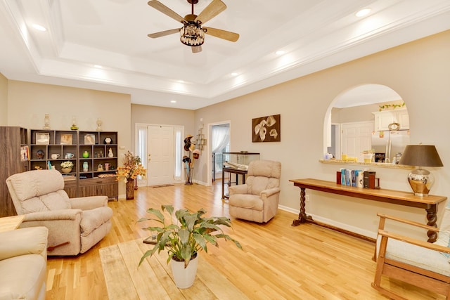 living room with ceiling fan, a raised ceiling, and light hardwood / wood-style floors