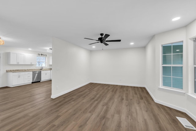 unfurnished living room with hardwood / wood-style floors, sink, and ceiling fan