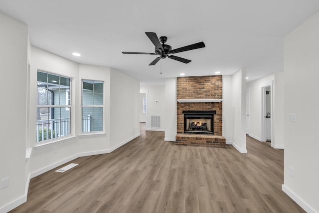 unfurnished living room featuring ceiling fan, a fireplace, and light hardwood / wood-style floors