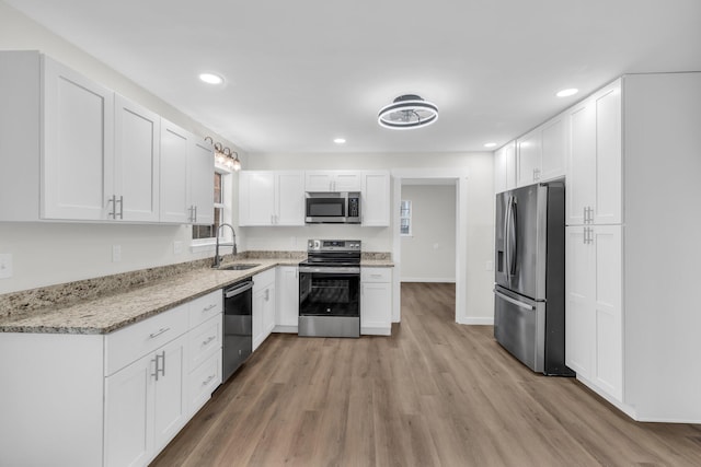 kitchen featuring light stone counters, stainless steel appliances, sink, and white cabinets