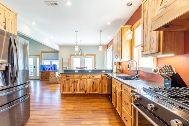 kitchen featuring sink, light hardwood / wood-style flooring, appliances with stainless steel finishes, decorative light fixtures, and kitchen peninsula