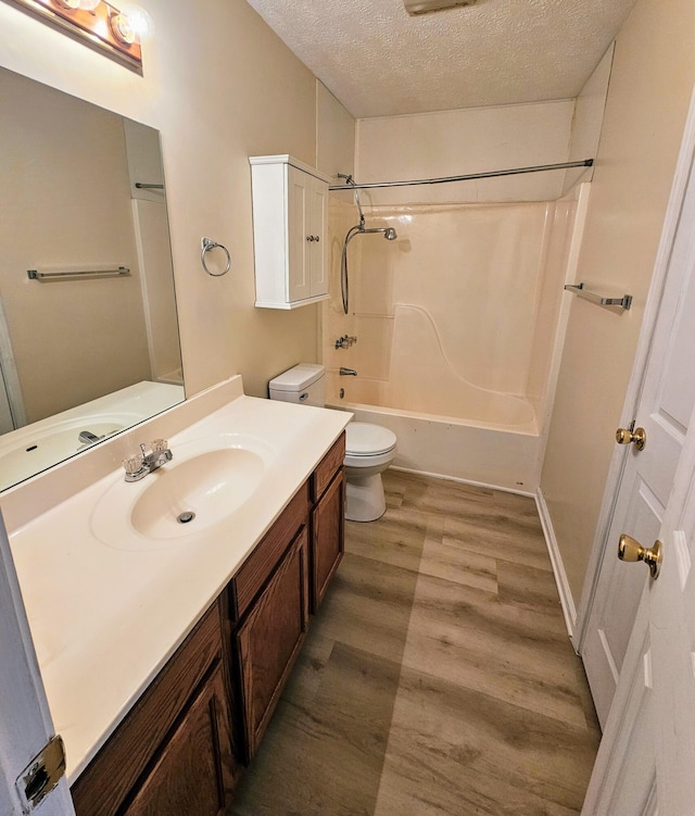 full bathroom featuring toilet, wood-type flooring, a textured ceiling, vanity, and shower / bath combination