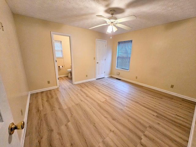 unfurnished bedroom featuring ceiling fan, a textured ceiling, light hardwood / wood-style floors, and ensuite bath