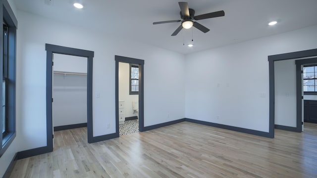 unfurnished bedroom with ceiling fan, connected bathroom, light hardwood / wood-style floors, a spacious closet, and a closet